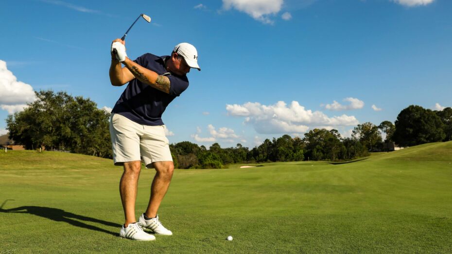 Man swinging golf club at a ball on a golf course