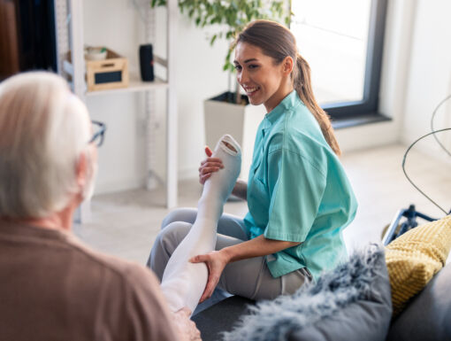 Smiling nurse assisting elderly male with compression stockings