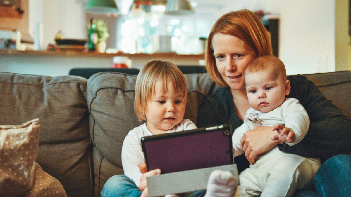 Mother reading to young children from tablet