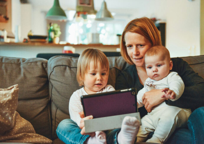 Mother reading to young children from tablet