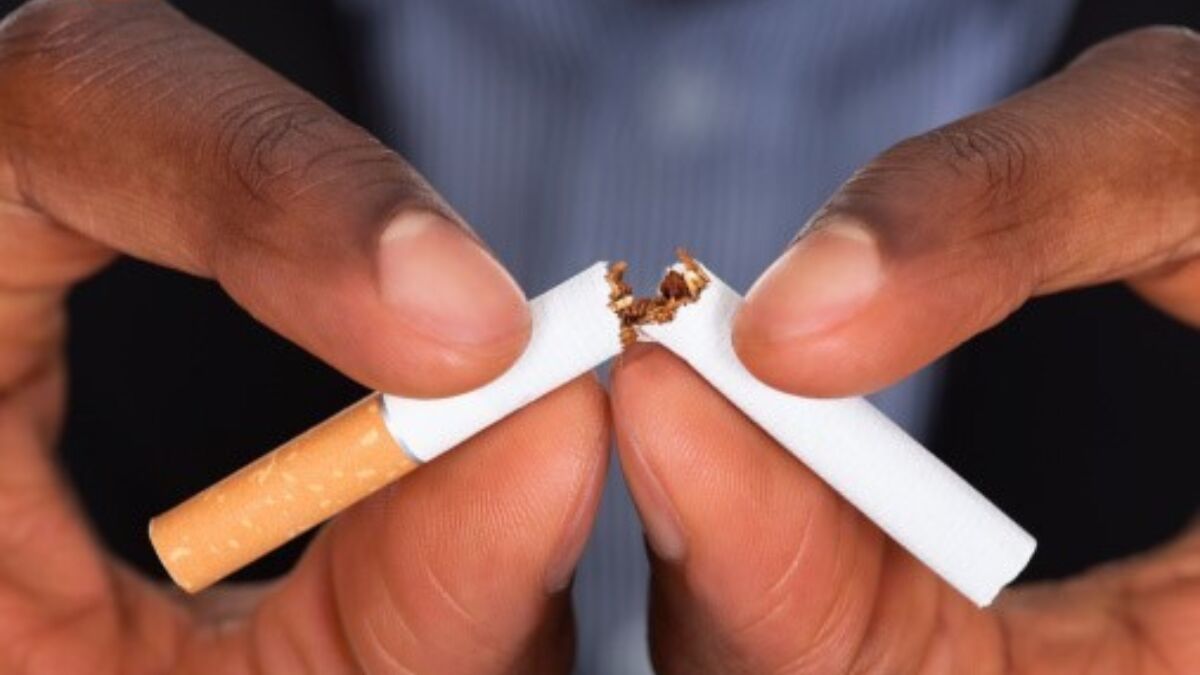 A person breaking a cigarette into two pieces