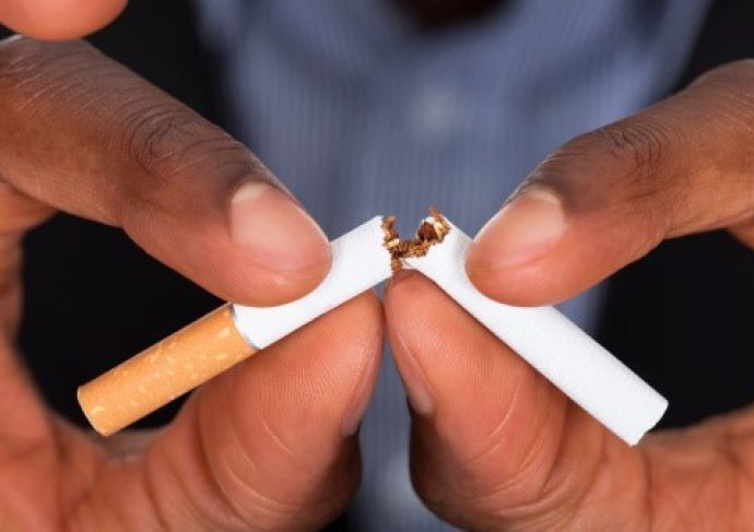 A person breaking a cigarette into two pieces