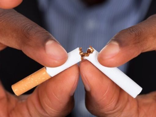 A person breaking a cigarette into two pieces