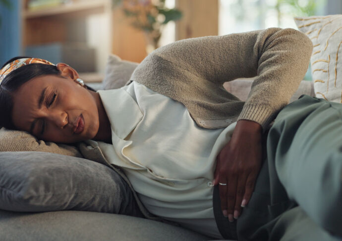Woman laying on the couch clutching abdomen