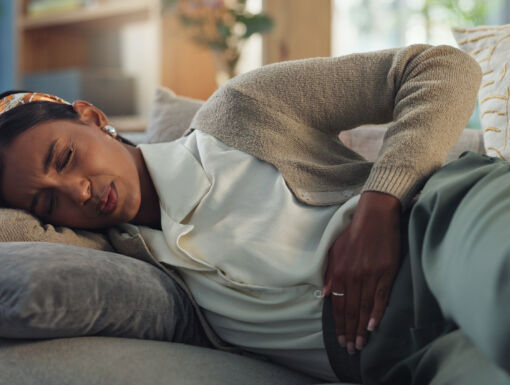 Woman laying on the couch clutching abdomen