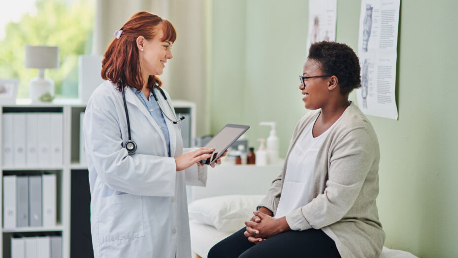 Woman sitting on exam table smiling and talking to her doctor