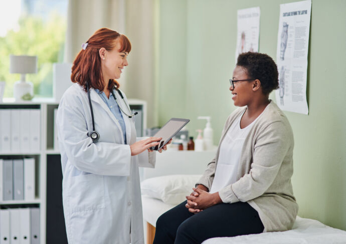Woman sitting on exam table smiling and talking to her doctor
