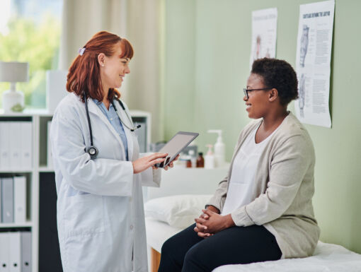 Woman sitting on exam table smiling and talking to her doctor