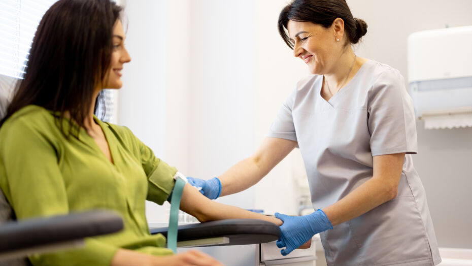 Woman getting blood drawn from female nurse in scrubs