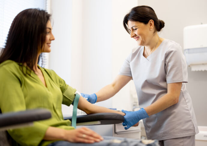 Woman getting blood drawn from female nurse in scrubs