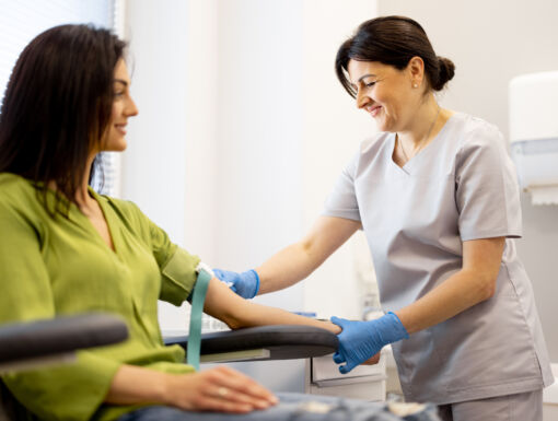 Woman getting blood drawn from female nurse in scrubs