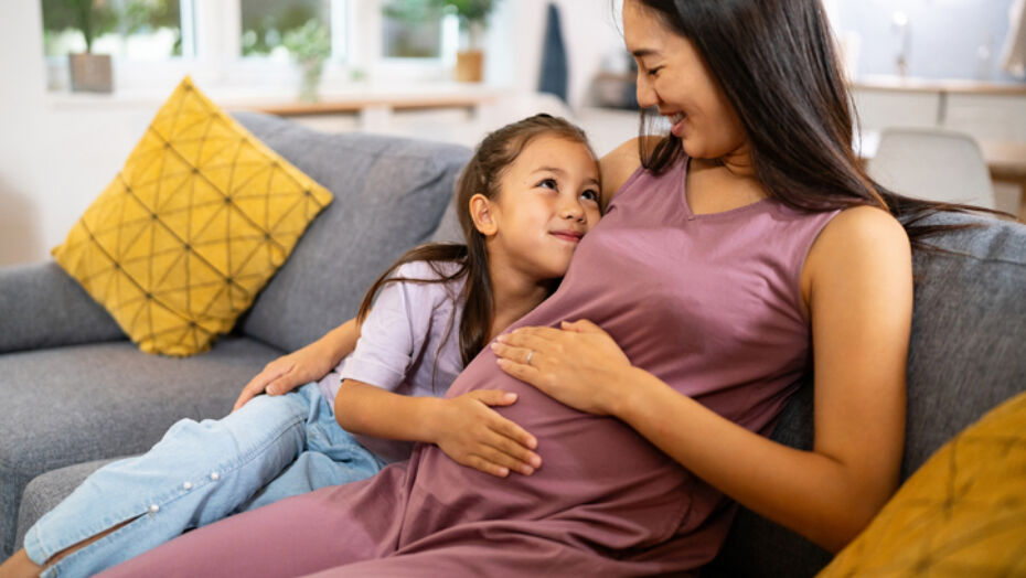 Pregnant mom sitting on sofa with daughter