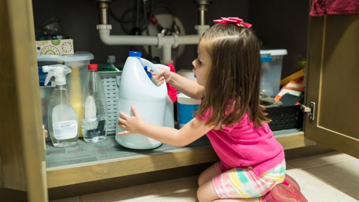 Little girl with bleach under sink