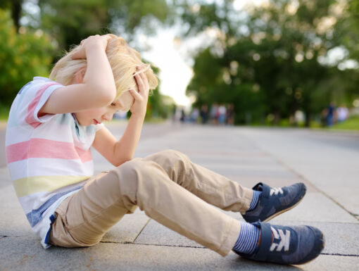 Boy sitting on the street holding his head