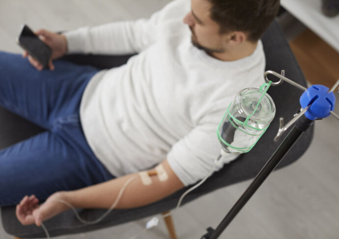 Man with cellphone in hand and IV in arm