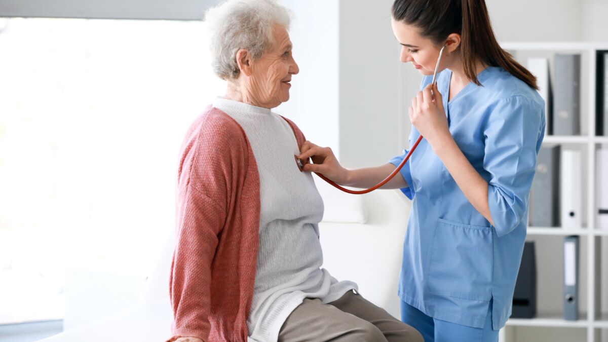 Nurse listening to older patients heart