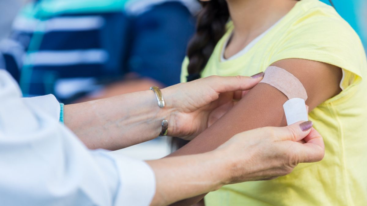 Person getting a Band-Aid placed on their arm after a shot