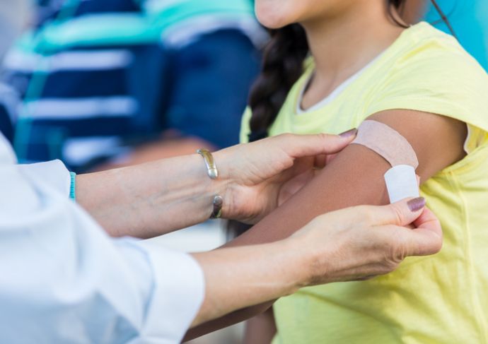 Person getting a Band-Aid placed on their arm after a shot