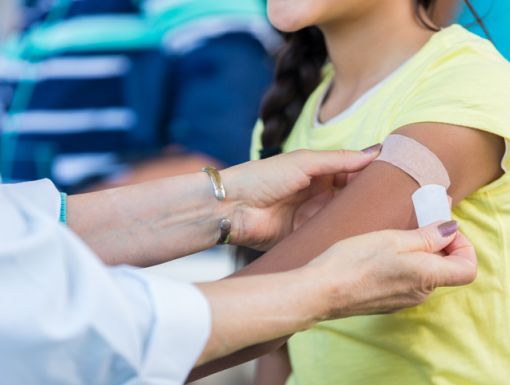 Person getting a Band-Aid placed on their arm after a shot
