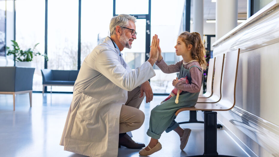 Pediatric liver transplant patient high fiving doctor in a waiting room