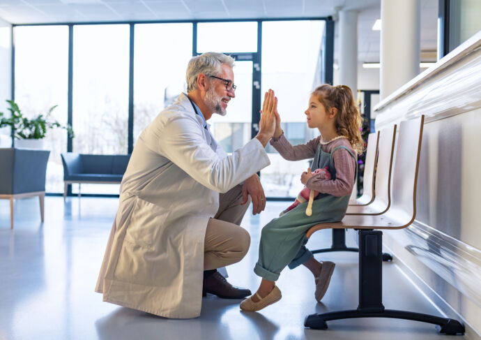 Pediatric liver transplant patient high fiving doctor in a waiting room
