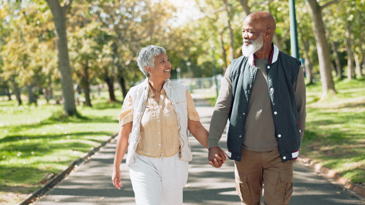 Man and woman holding hands walking outside.