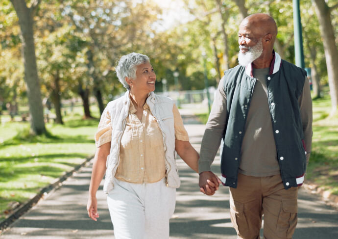 Man and woman holding hands walking outside.