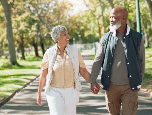 Man and woman holding hands walking outside.