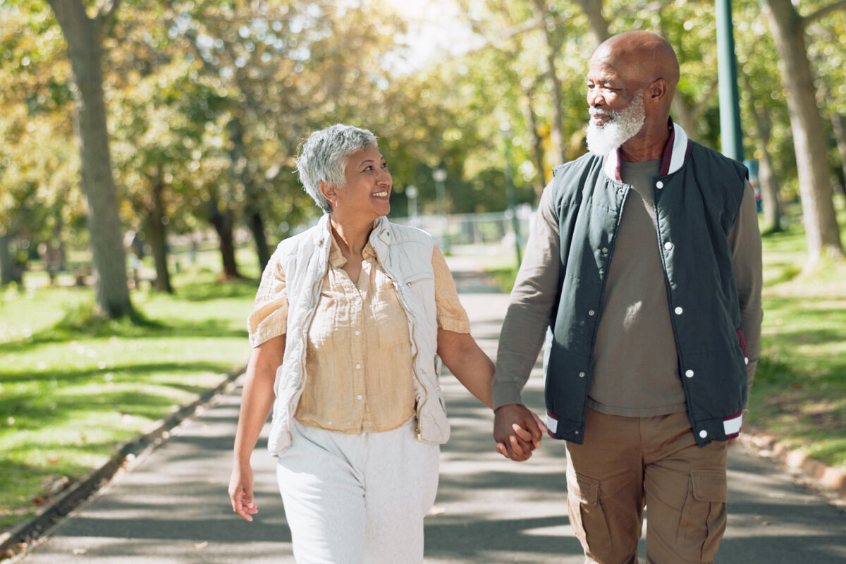 Older man and women walking outside holding hands