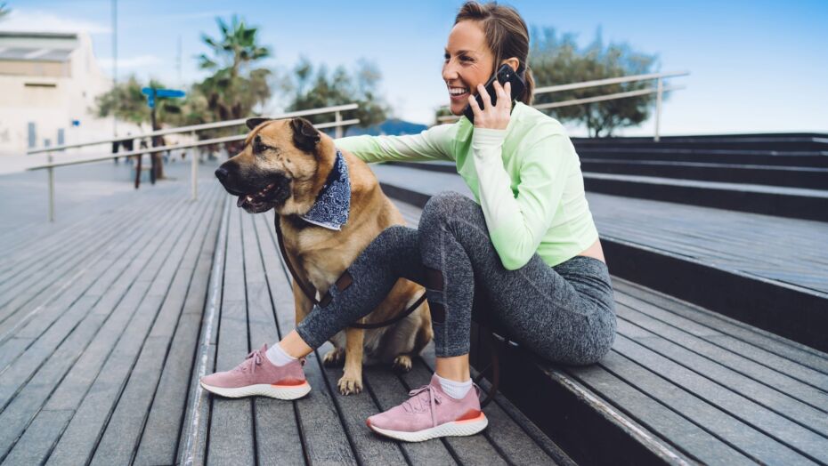 Woman on phone sitting on steps with dog