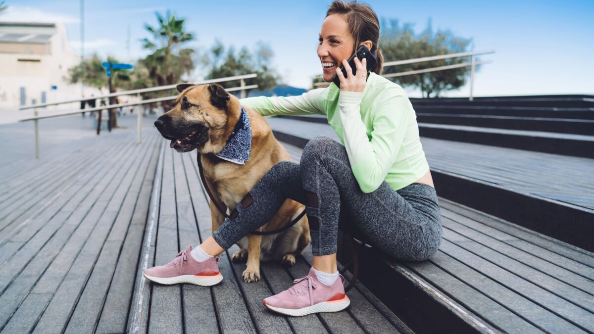 Woman on phone sitting on steps with dog