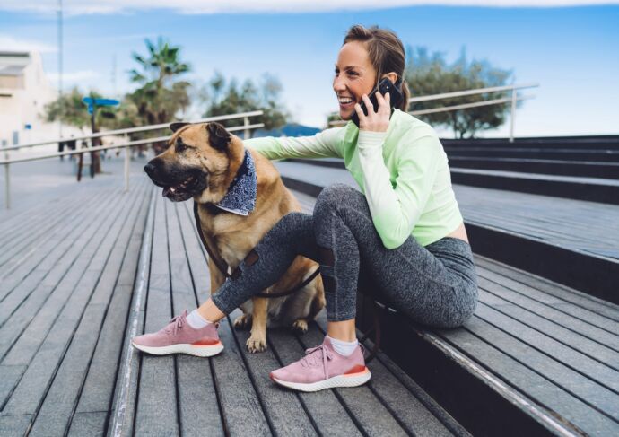 Woman on phone sitting on steps with dog
