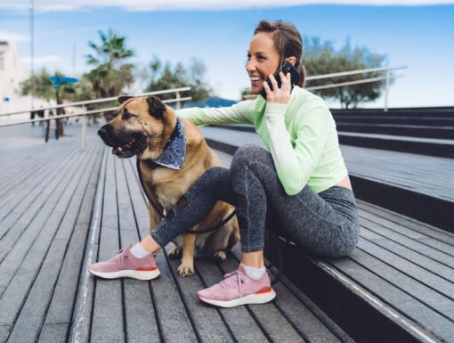 Woman on phone sitting on steps with dog