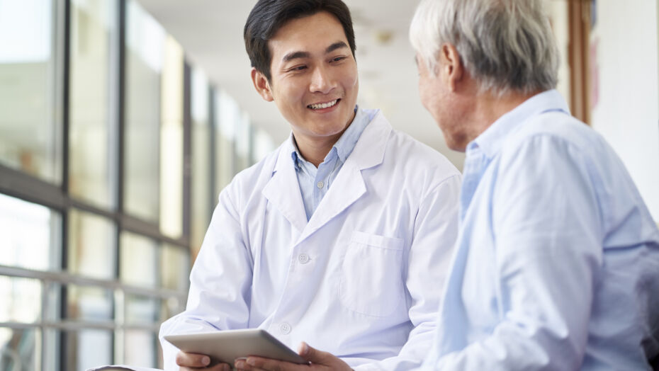 Male doctor talking to older patient in waiting room