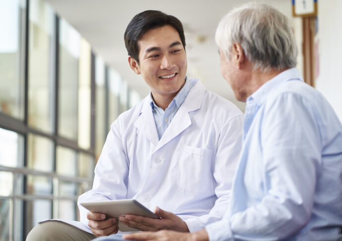 Male doctor talking to older patient in waiting room
