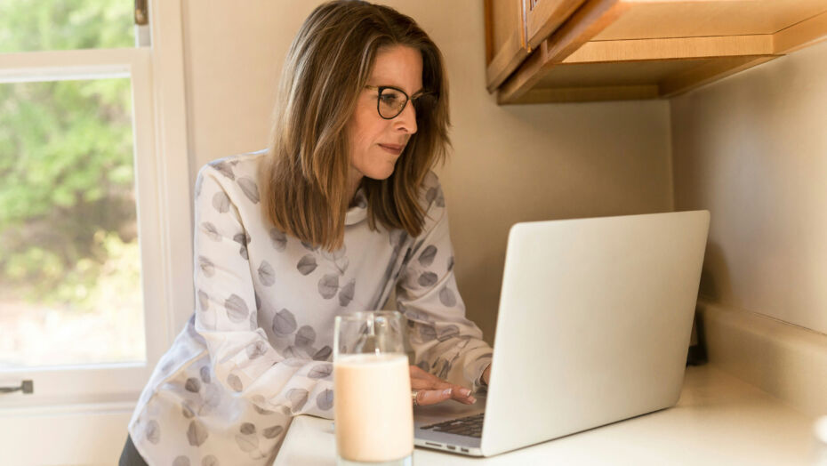 Woman with glass of milk and laptop