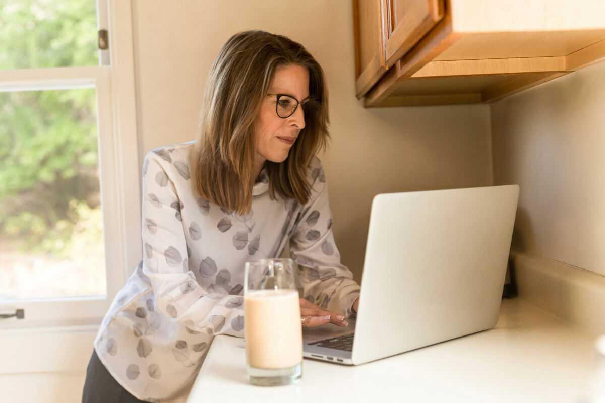 Woman with glass of milk and laptop