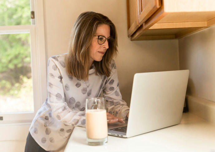 Woman with glass of milk and laptop