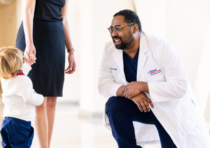 Doctor smiling and kneeling to talk to child and their mom