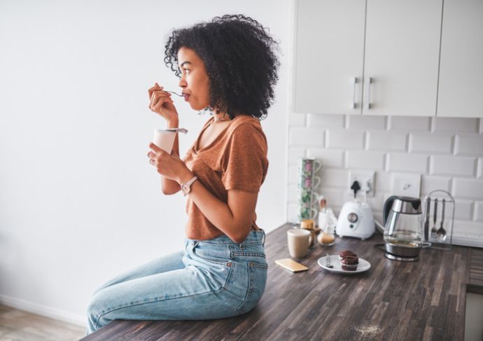 Girl sitting on counter eating probiotics