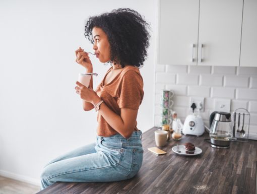 Girl sitting on counter eating probiotics