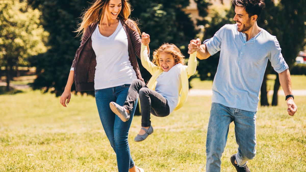 Parents swinging child by arms