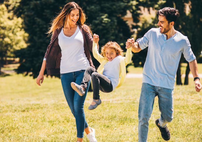 Parents swinging child by arms