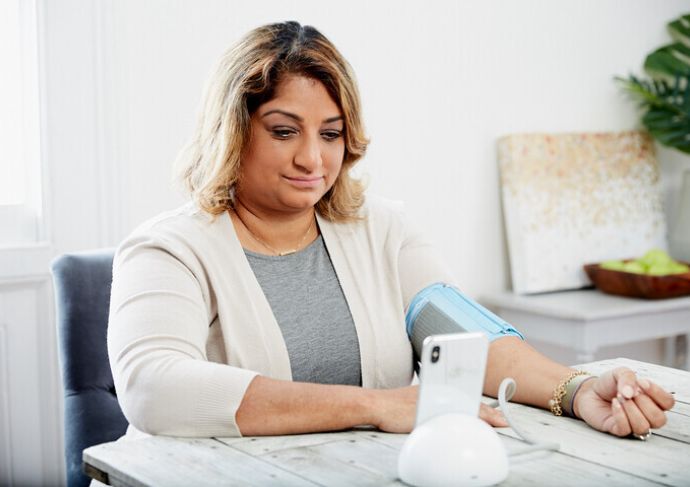 Woman checking her blood pressure at her desk