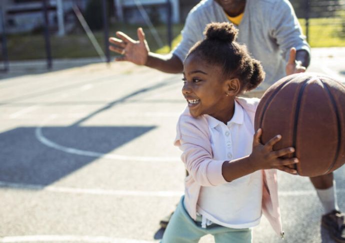 Little girl child playing basketball with father
