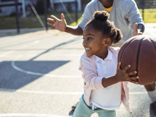 Little girl child playing basketball with father