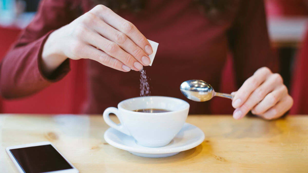 Woman adding sugar to coffee