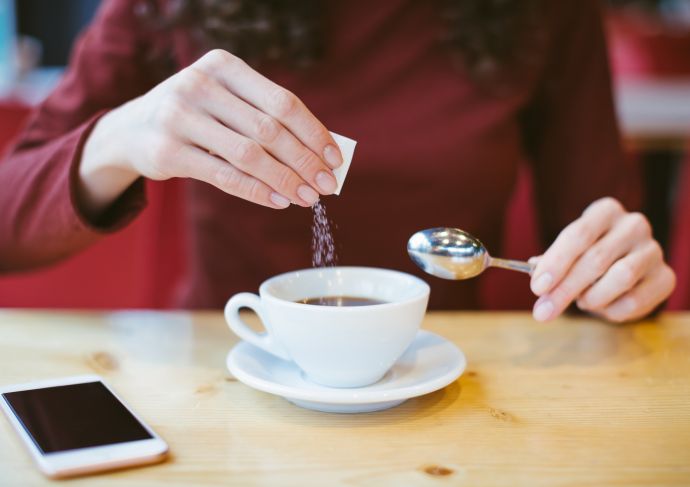 Woman adding sugar to coffee