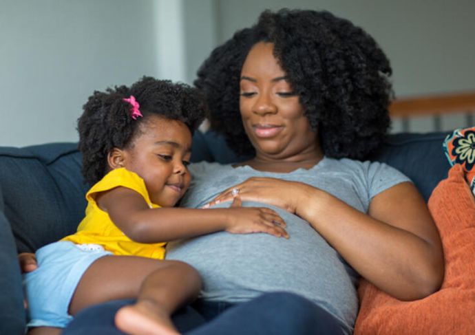 Pregnant woman sitting on the couch with her daughter