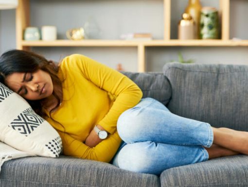 Woman laying on couch holding her stomach